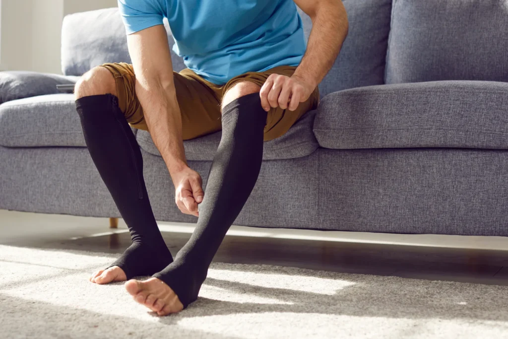 Man on couch putting on long black socks