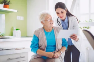Older woman talking to doctor who is holding an tablet
